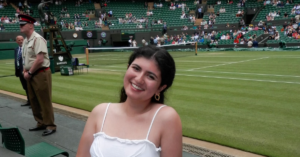 Student in all white smiles at the camera while at Wimbledon.