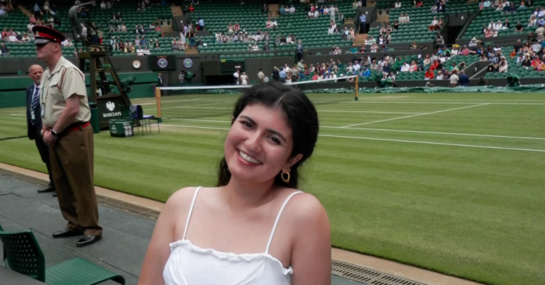 Student in all white smiles at the camera while at Wimbledon.
