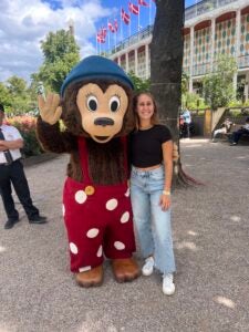 Student standing next to a disney character at a theme park