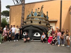 A group of students smile while posing next to a structure.