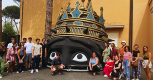 A group of students smile while posing next to a structure.