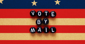 Black beads that spell out "vote by mail" behind an American flag.