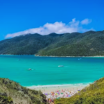 A sandy beach and bright blue water with beach goers in view