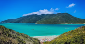 A sandy beach and bright blue water with beach goers in view