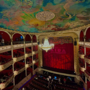 A historic theater with a chandelier and painted ceiling.