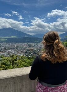 Student in black sweater overlooking a city and a mountain range.