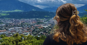 Student in black sweater overlooking a city and a mountain range.