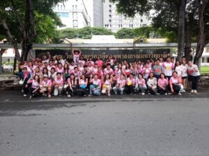 A group of students and teachers wearing pink posing for a group photo outside.