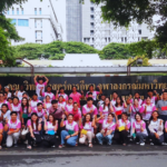 A group of students and teachers wearing pink posing for a group photo outside.