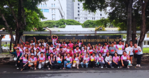 A group of students and teachers wearing pink posing for a group photo outside.