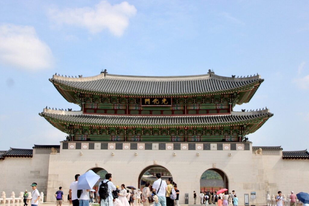 People stand in front of Gyeongbokgung palace entrance in South Korea