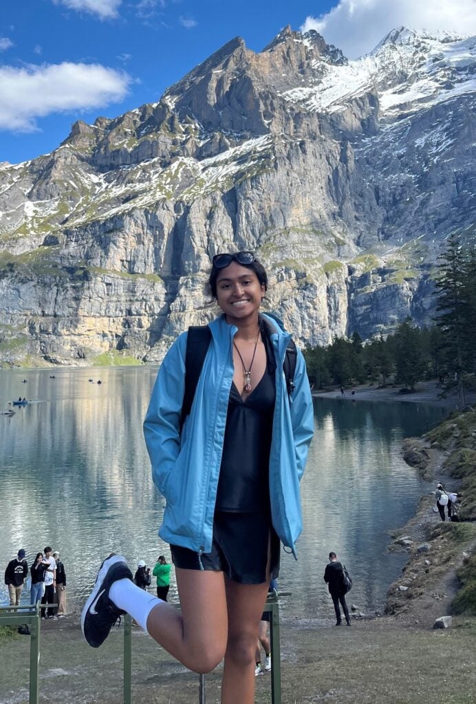 Anika poses at Oeschinensee Lake in Kandersteg, Switzerland, backdropped by the snow covered Swiss Alps