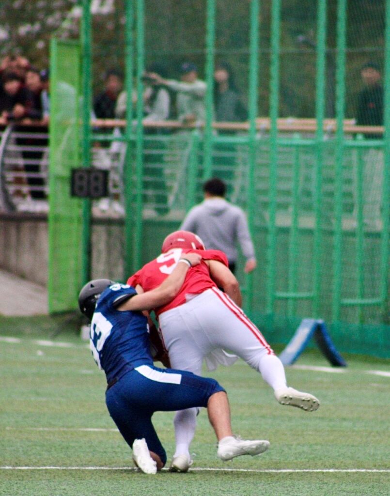 Football players tackle each other at a game where the Hanyang Lions faceoff against the Yonsei Eagles