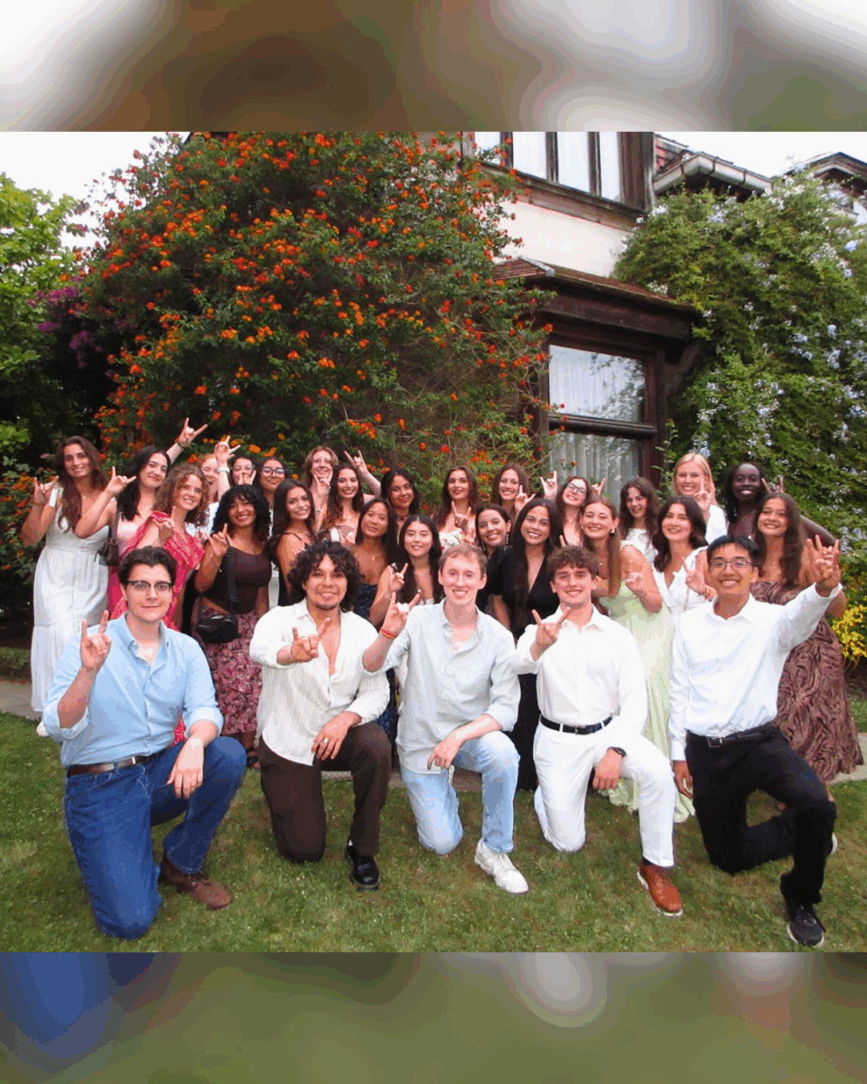 group of UT students posing in front of house doing hook 'em hand sign