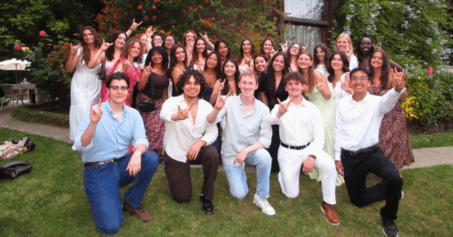 group of UT students posing in front of house doing hook 'em hand sign