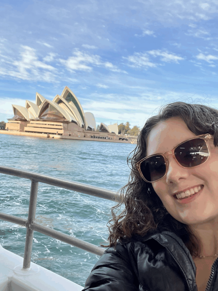 Amber smiles on a boat with the Sydney Opera House in view behind her