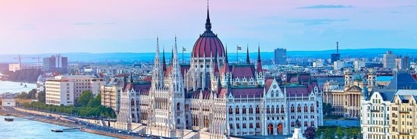 Hungarian Parliament Building on the Danube River in Budapest with a cityscape backdrop.