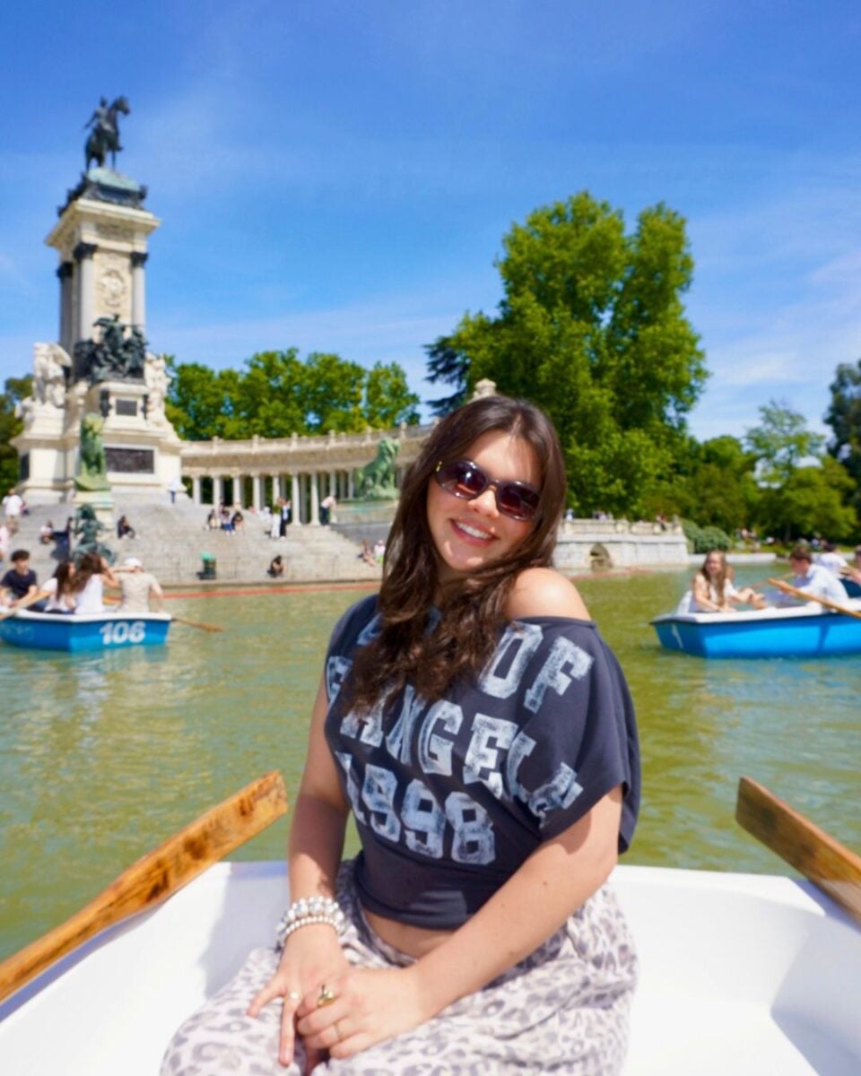 A woman in a boat on a lake with a monument and boats in the background.
