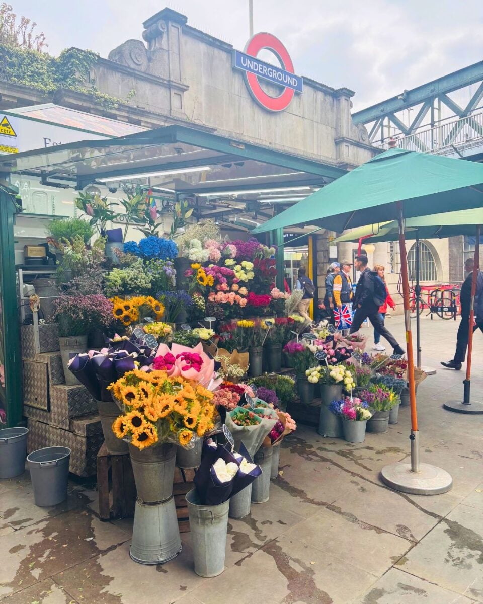 Flower stand with various colorful bouquets in front of an underground station entrance.