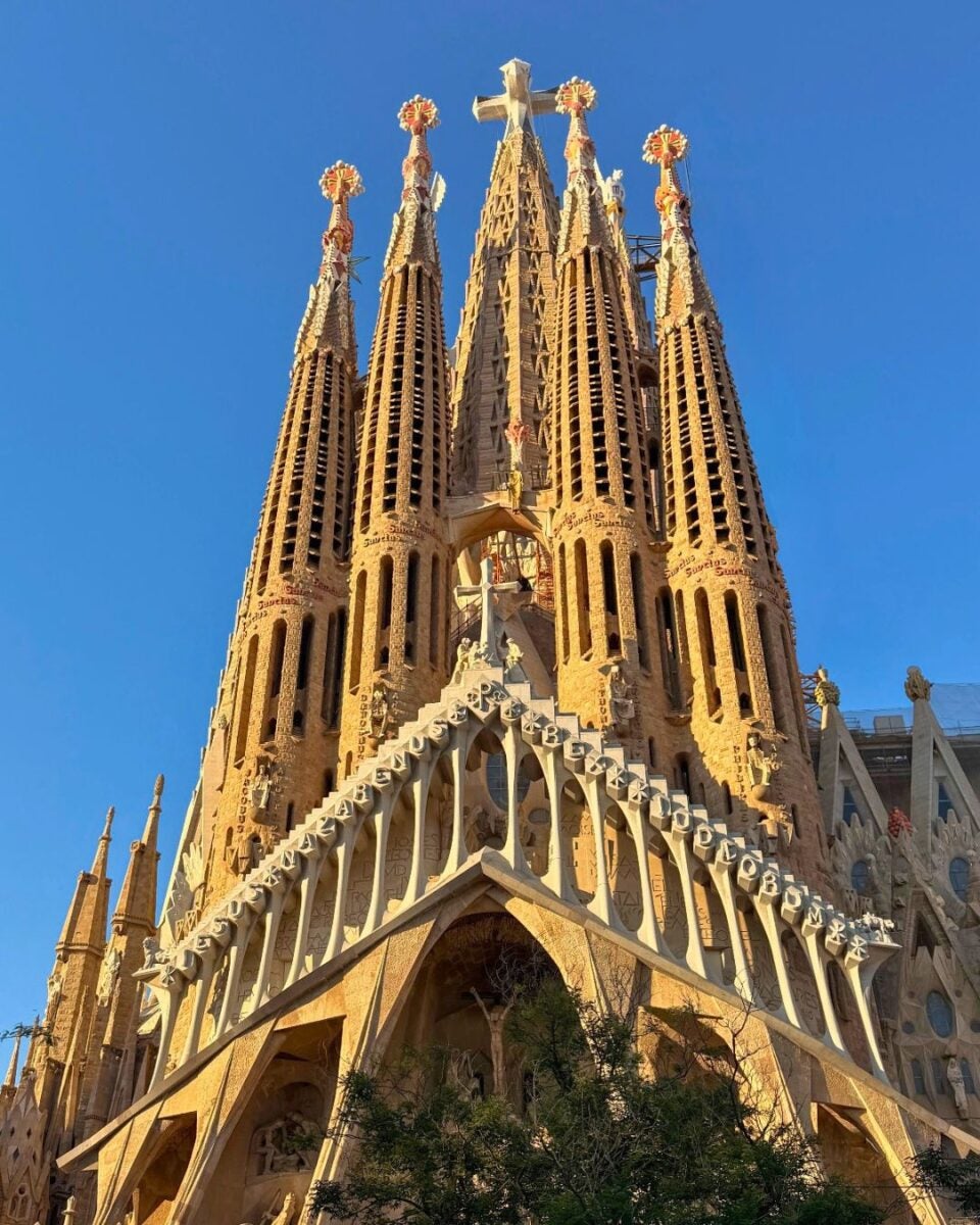 The towering spires of Barcelona's Sagrada Familia church against a clear blue sky.