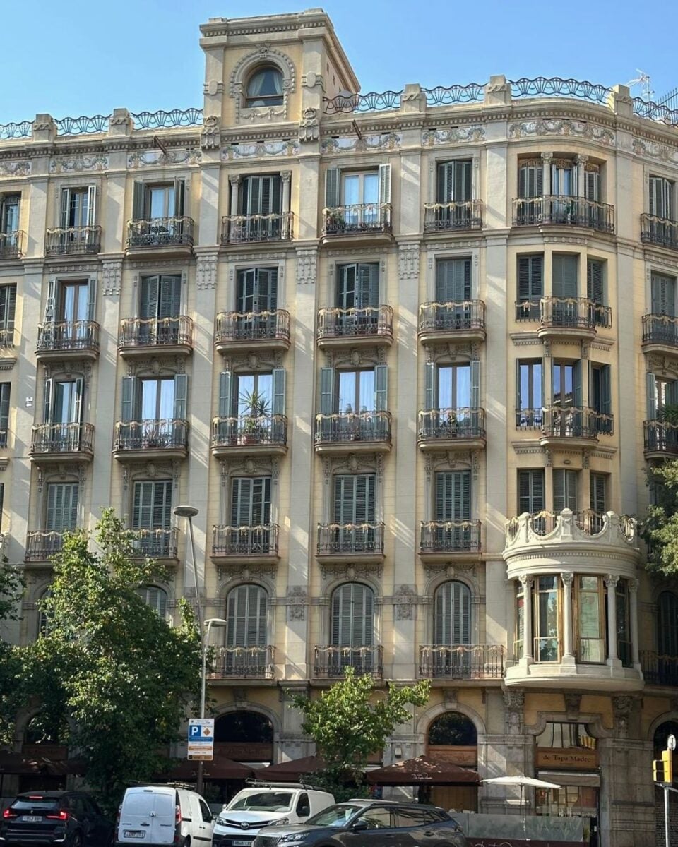 Elegant historic building with ornate balconies and large windows under a clear blue sky in an urban setting.
