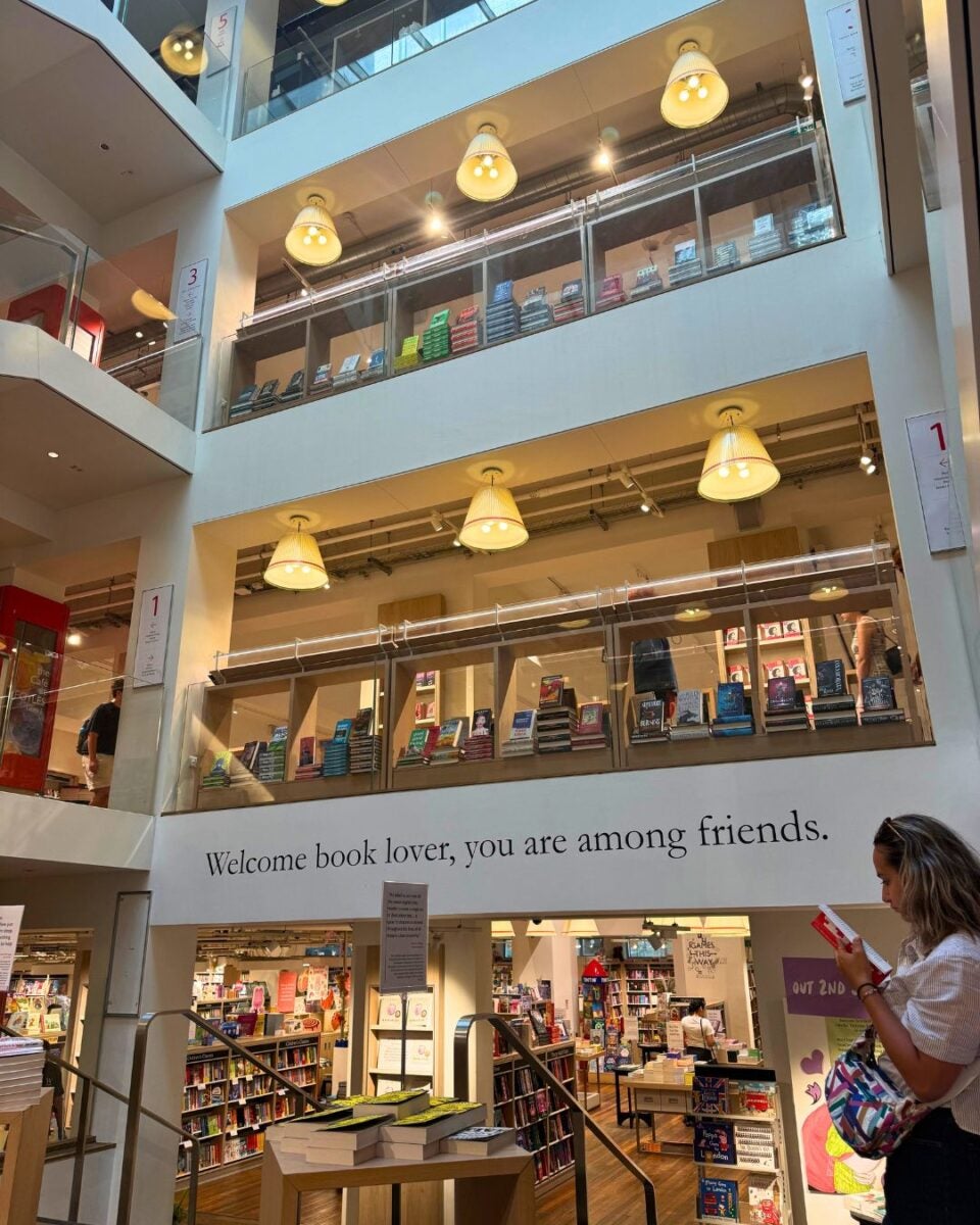 Interior view of a multi-level bookstore with shelves filled with books and a welcoming quote on the wall.