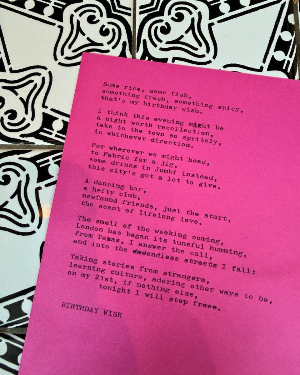 Pink paper with a typed poem titled 'BIRTHDAY WISH' placed on a black and white patterned surface.